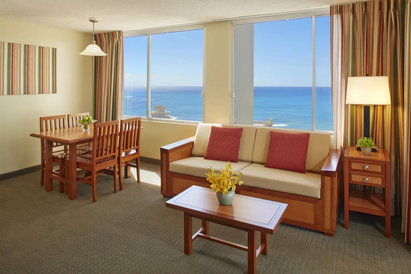 Ocean-view one-bedroom suite living area with sofa and dining table at Pacific Monarch Hotel.