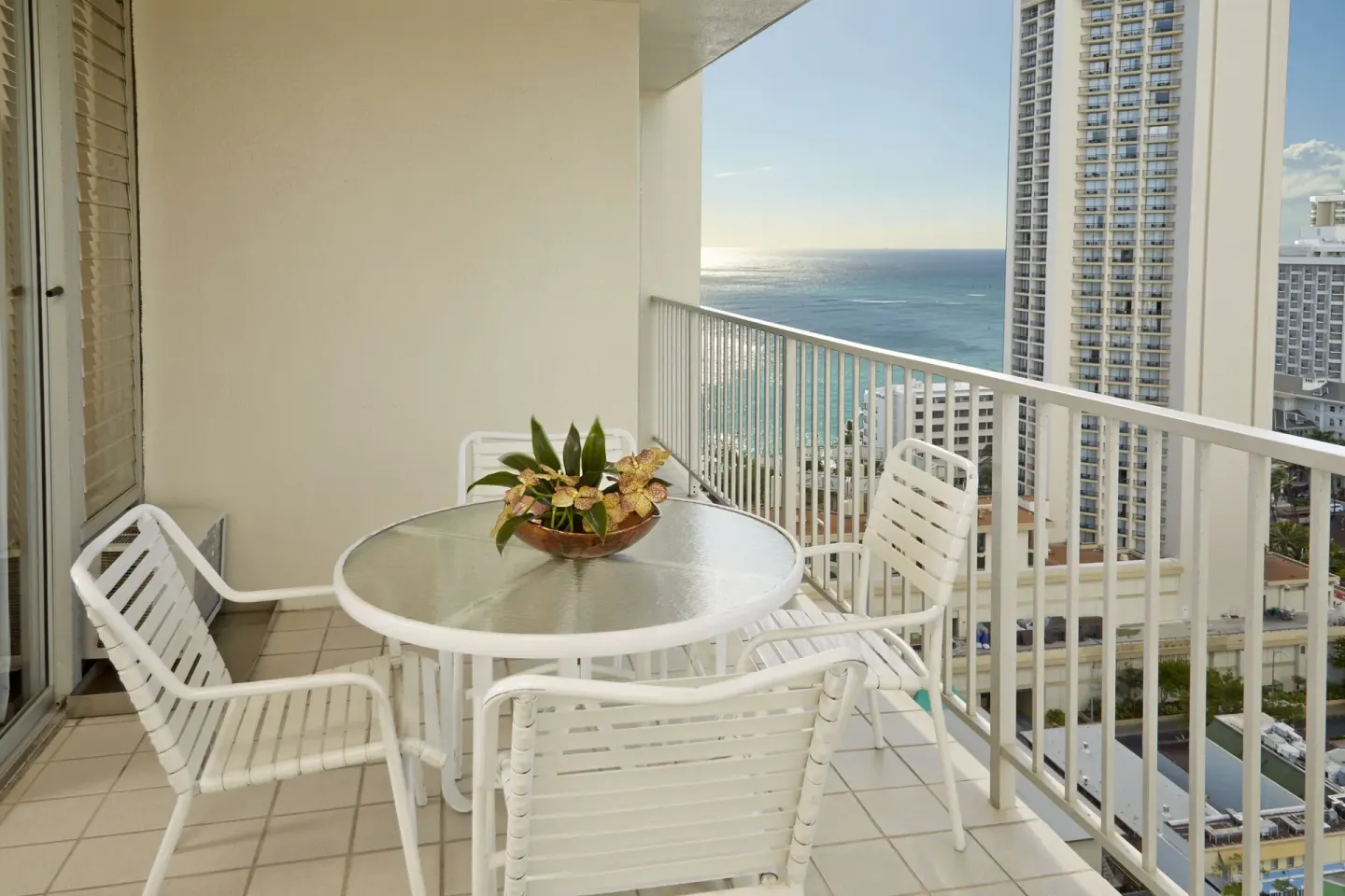 One-bedroom suite balcony with table, chairs, and ocean view at Pacific Monarch Hotel.