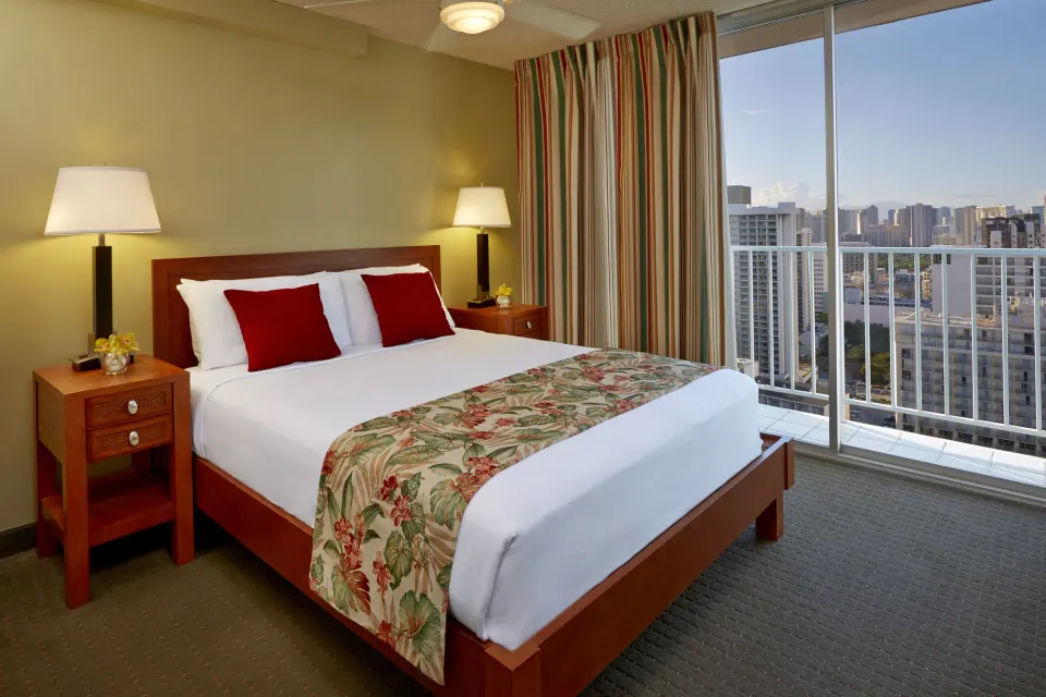 One-bedroom suite bed beside floor-to-ceiling windows at Pacific Monarch Hotel.