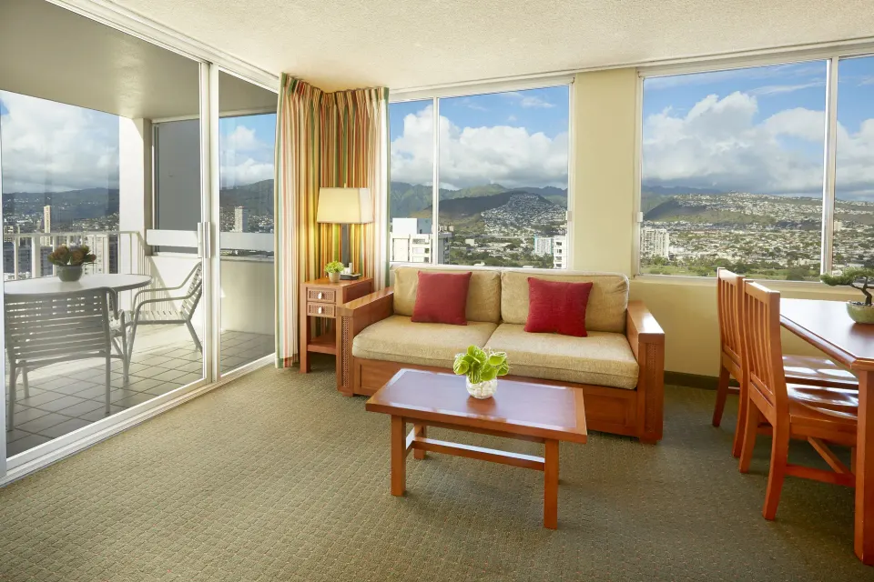 One-bedroom suite living room with balcony and mountain views at Pacific Monarch Hotel.