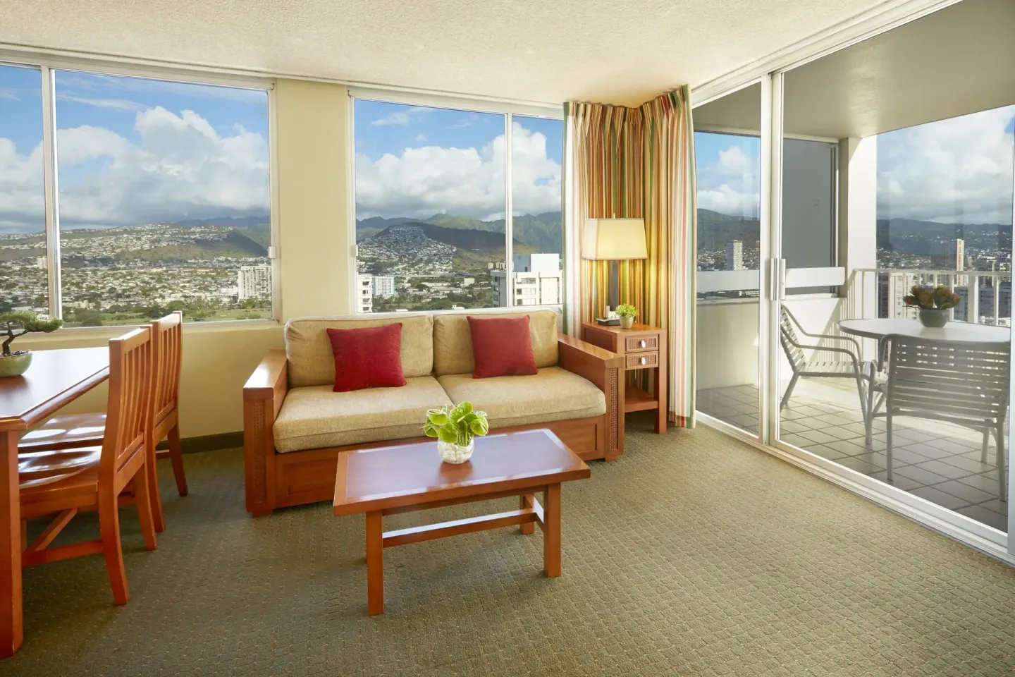 One-bedroom suite living room with sofa, desk, and balcony doors at Pacific Monarch Hotel.