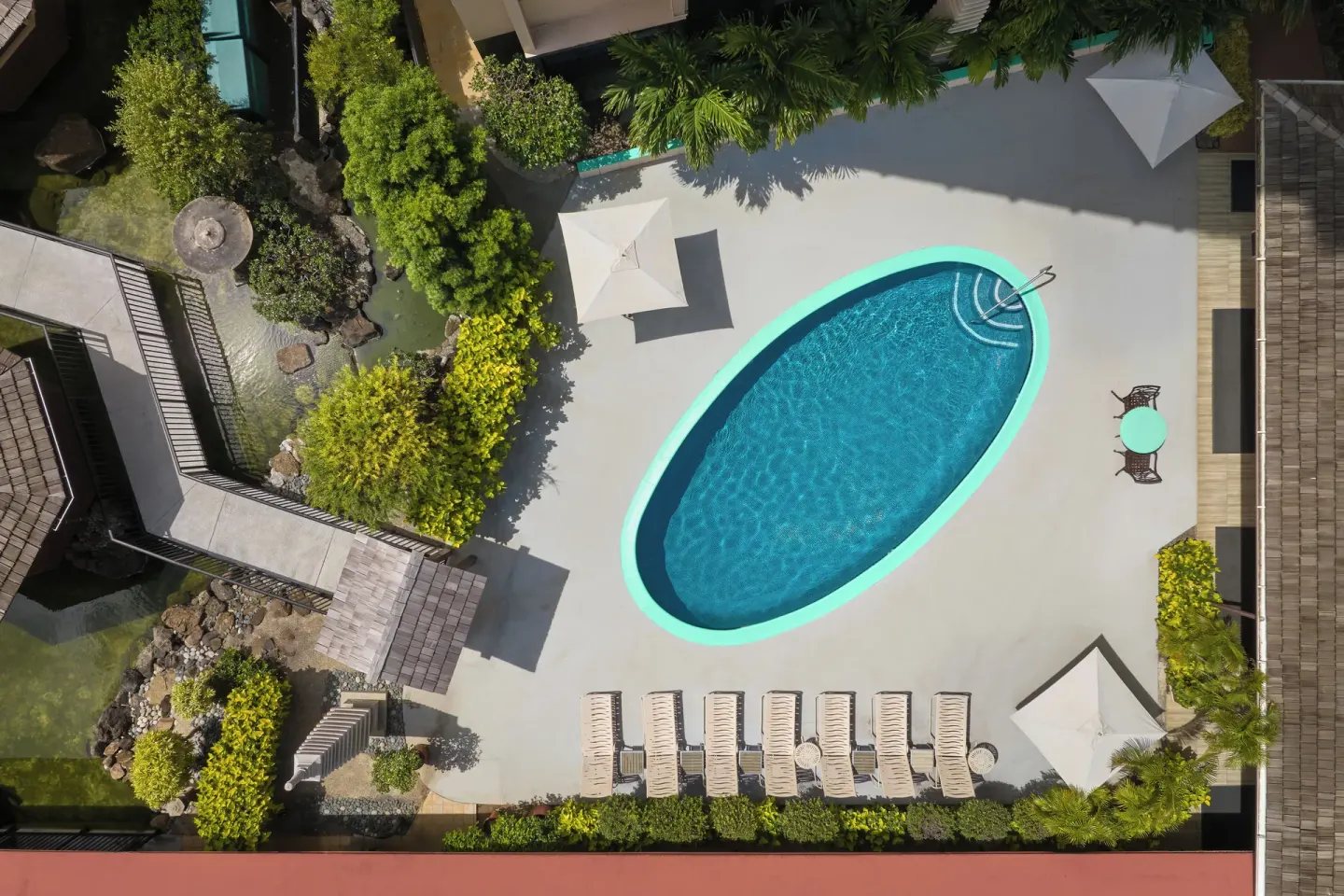 Aerial view of the Pagoda Hotel pool deck with an oval pool, lounge chairs, umbrellas, and landscaping.