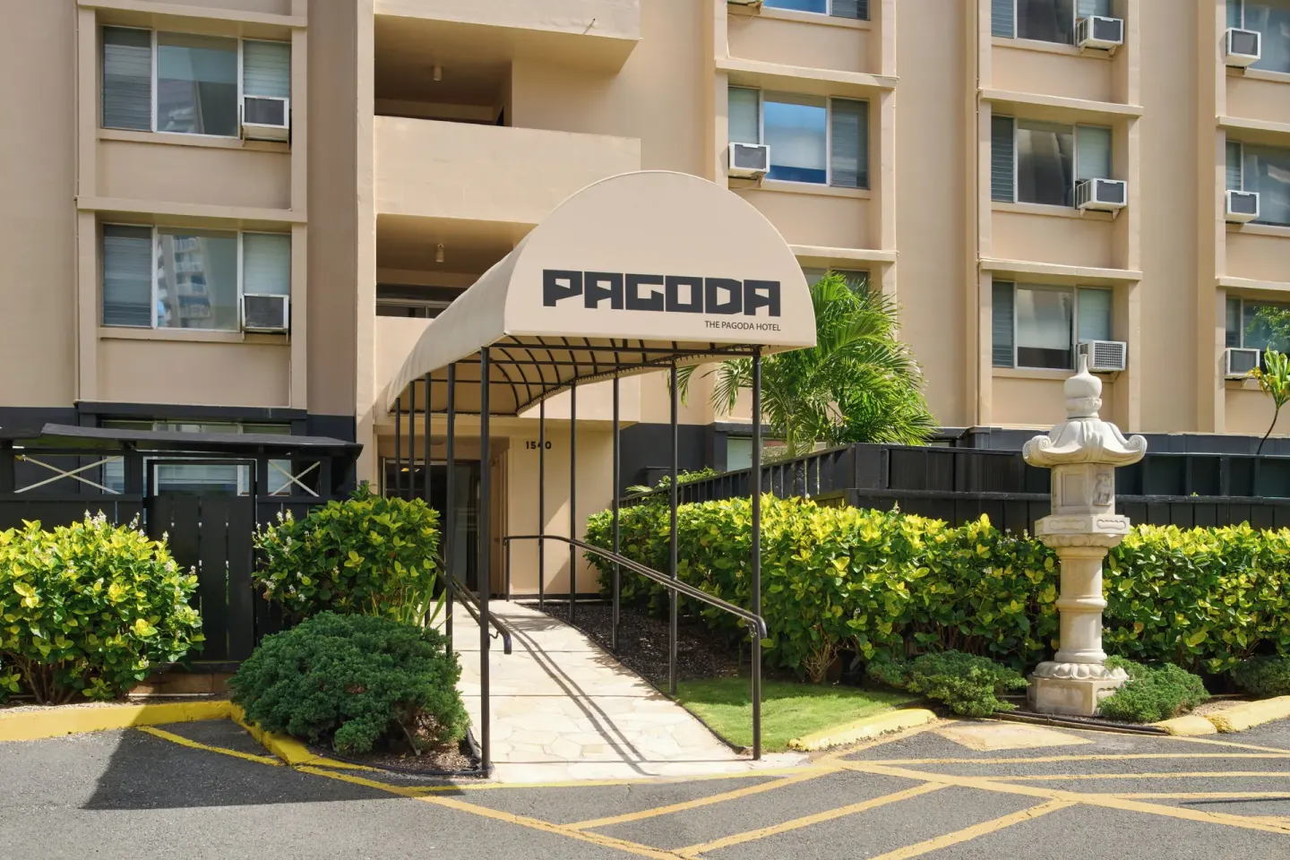 Covered walkway entrance with Pagoda signage and landscaping at Pagoda Hotel.