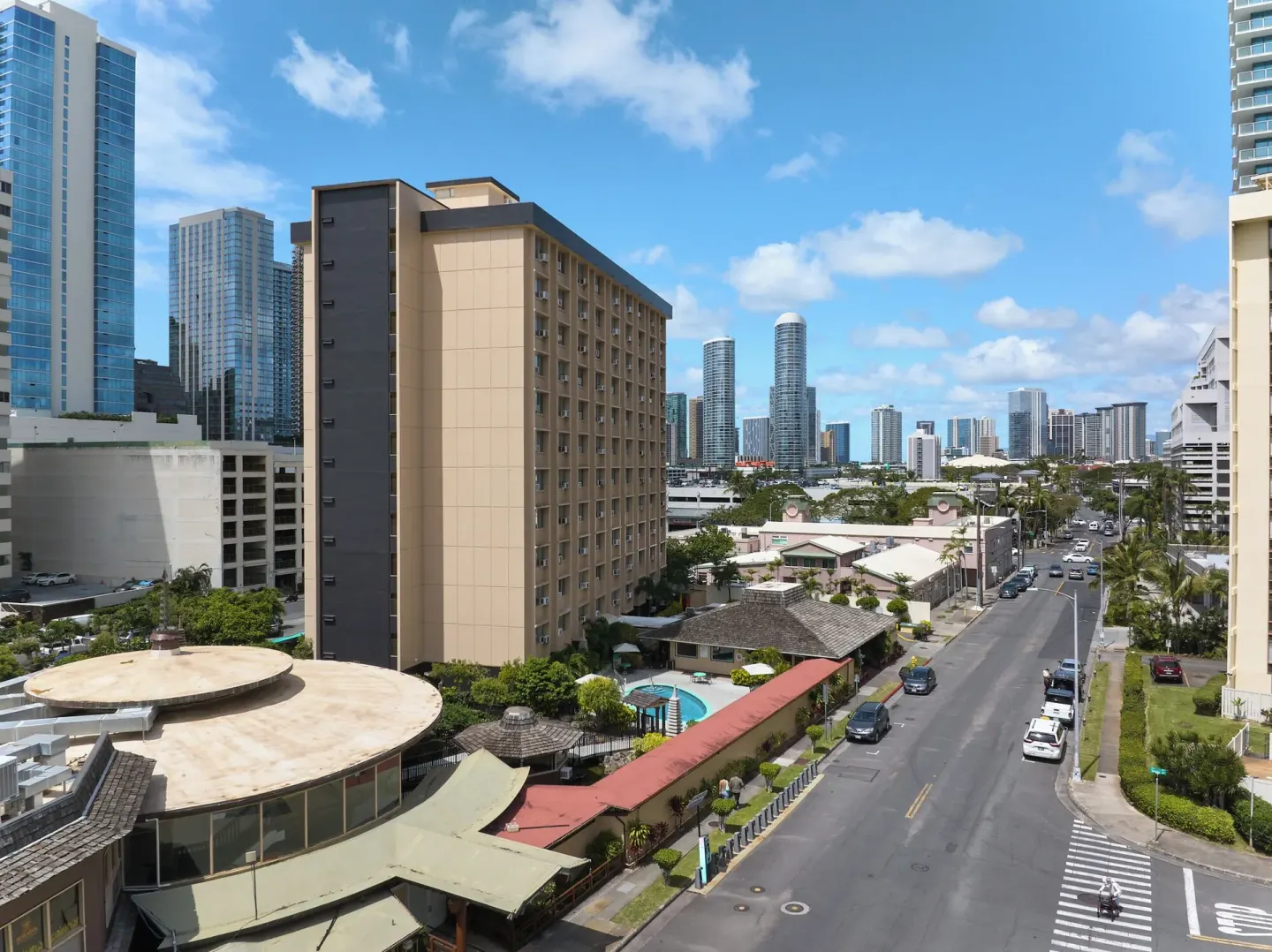 Pagoda Hotel exterior with pool courtyard, street, and Honolulu skyline.