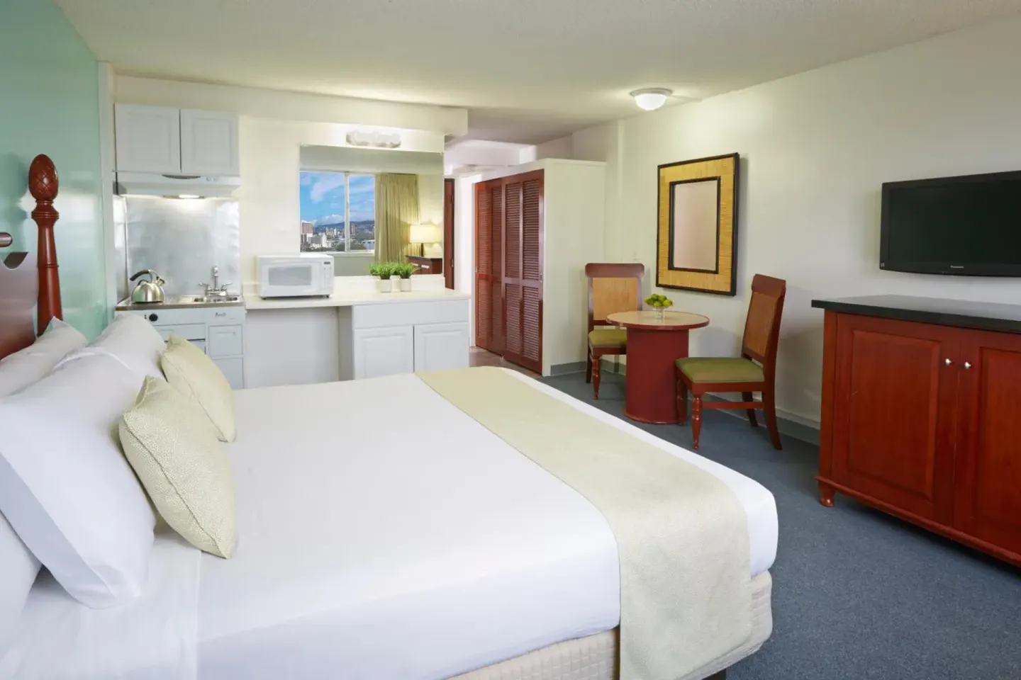 Guest room with king bed, kitchenette, dining table and TV at Pagoda Hotel.