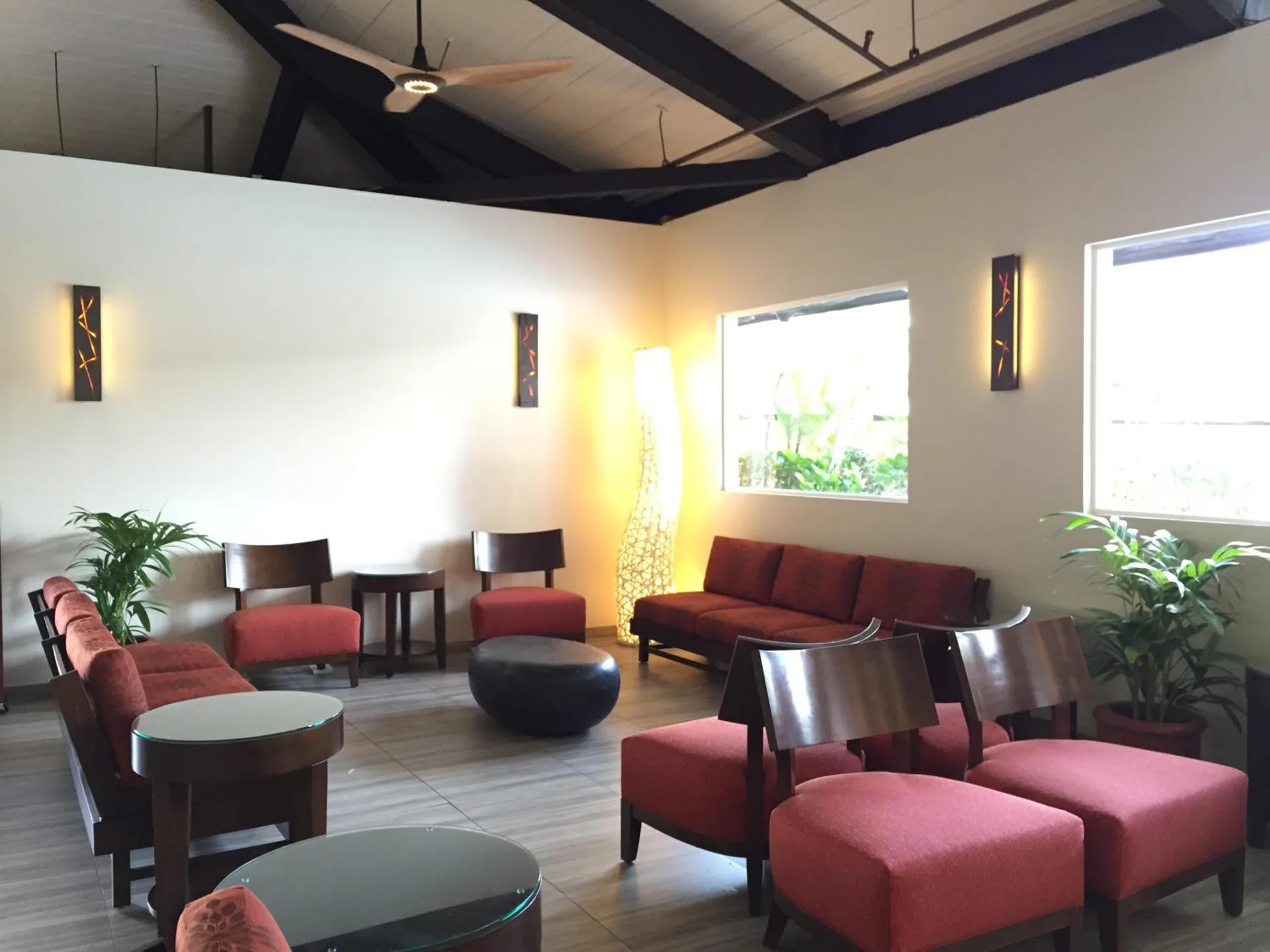 Lobby seating area with red chairs, plants, and tall windows at Pagoda Hotel.