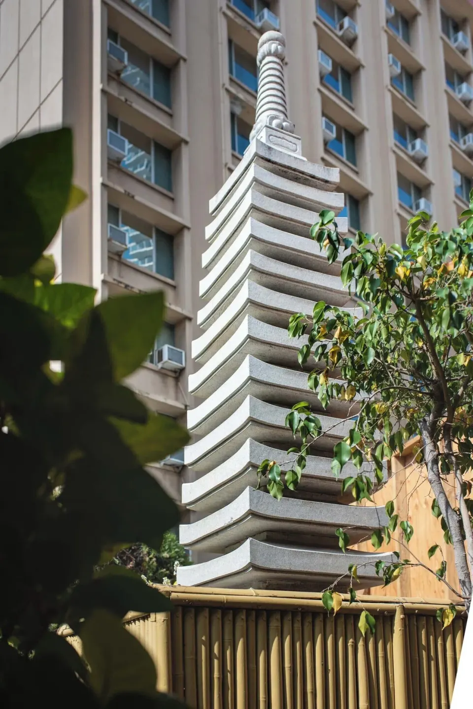 Pagoda-style stone tower framed by plants and the hotel building at Pagoda Hotel.
