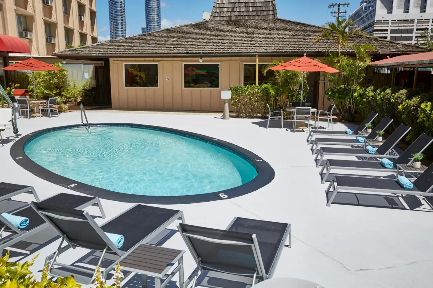 Pool deck with loungers and red umbrellas at Pagoda Hotel.