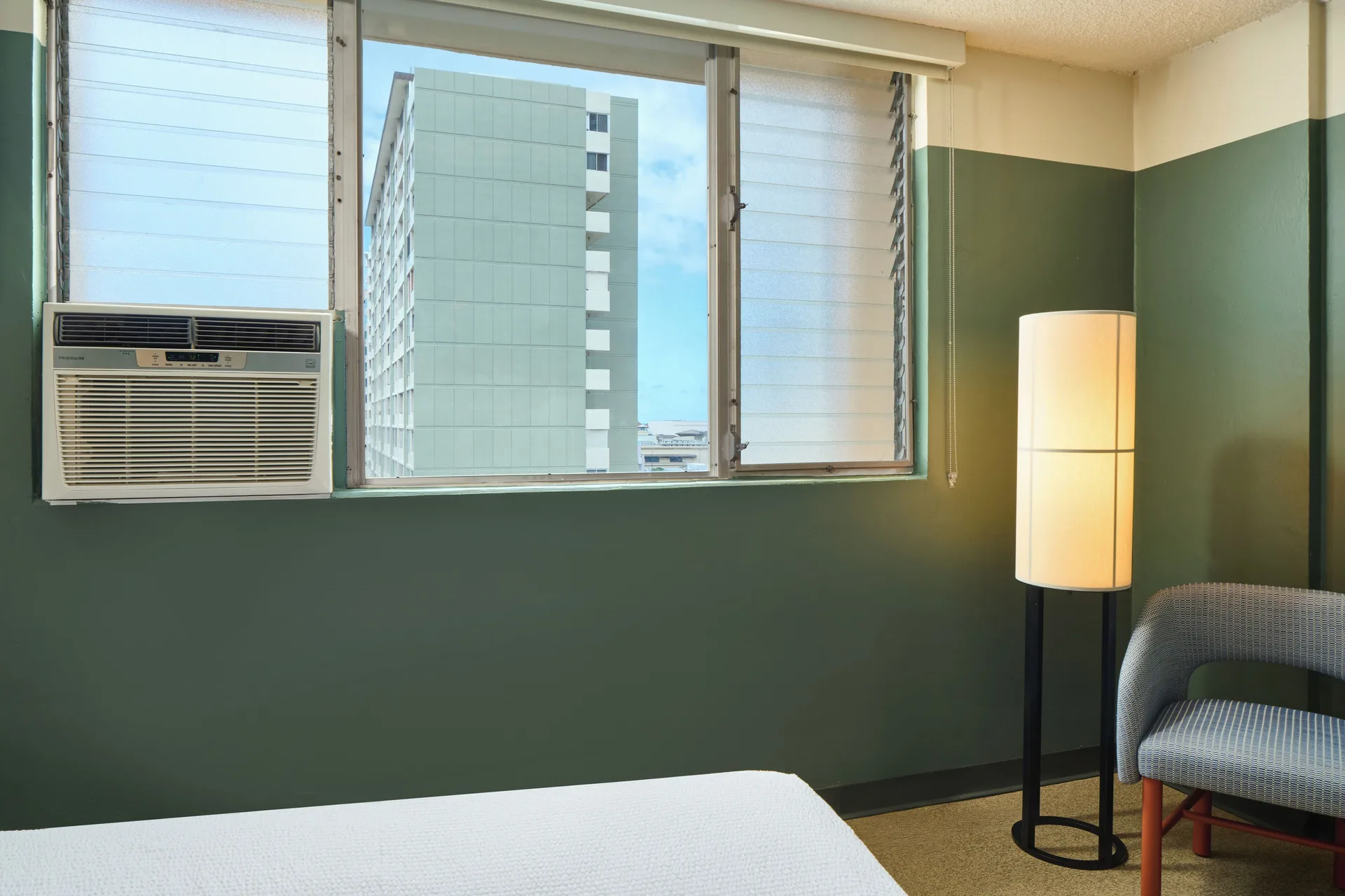 City View high-floor room at Pagoda Hotel with bed edge, windows, air conditioner, lamp and chair.
