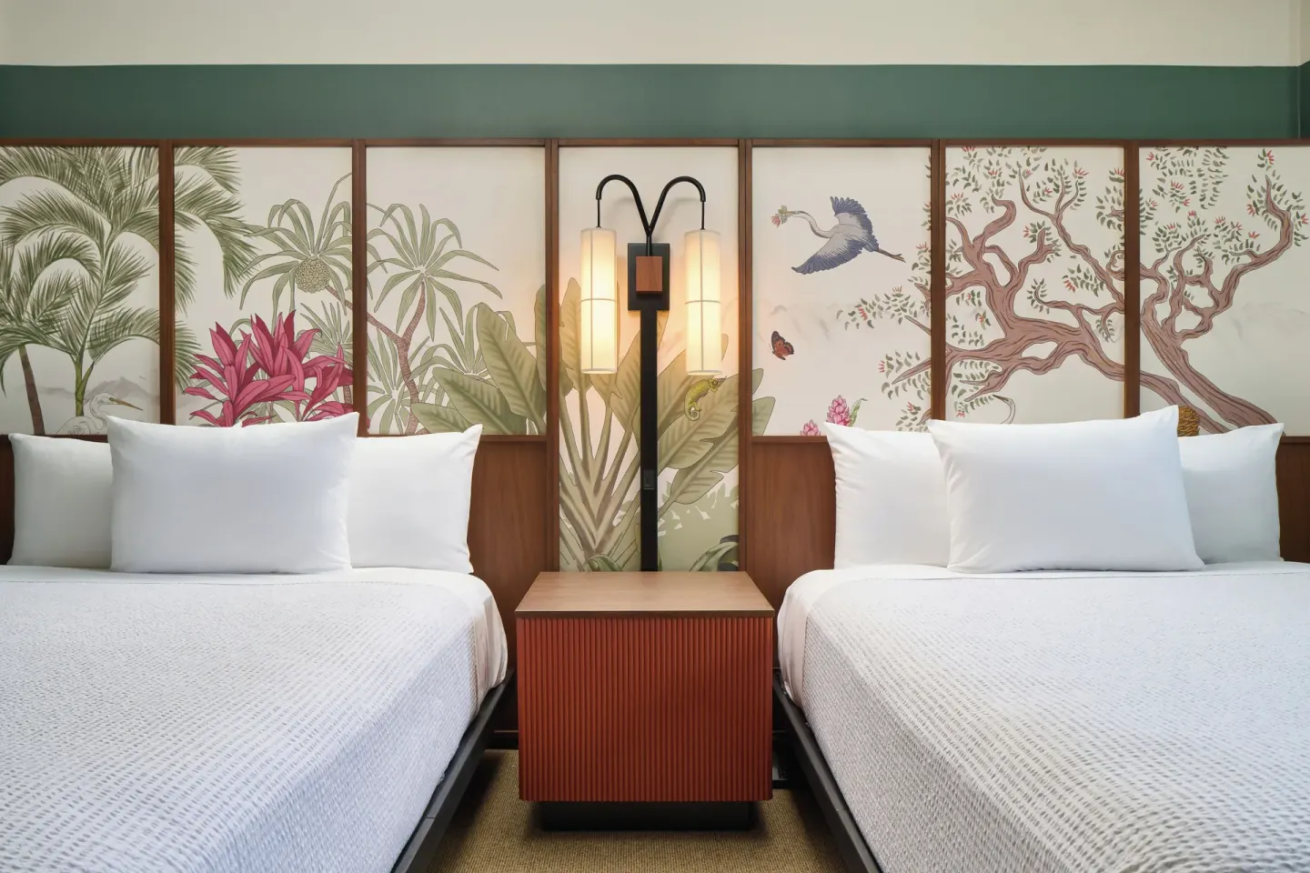Two beds with tropical headboards and a shared nightstand in a City View room at Pagoda Hotel.