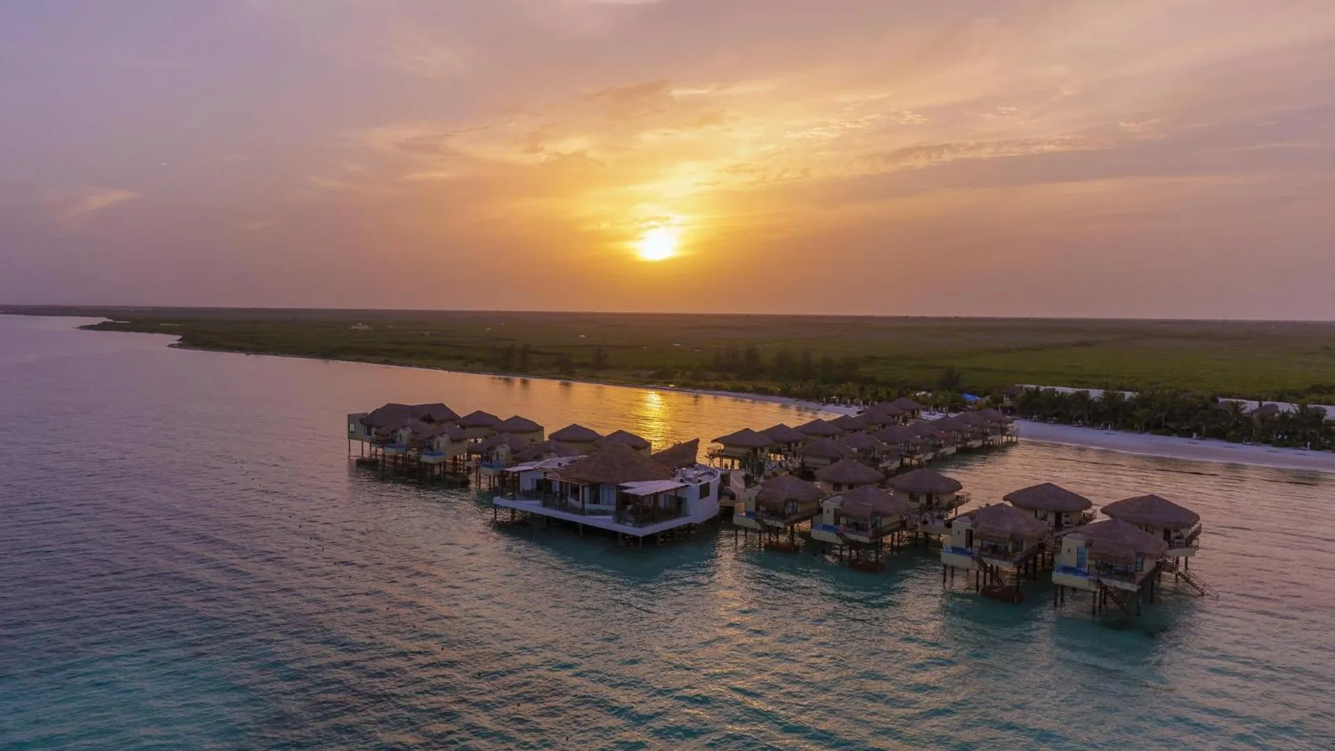 Aerial sunset view of overwater bungalows at Palafitos Overwater Bungalows.