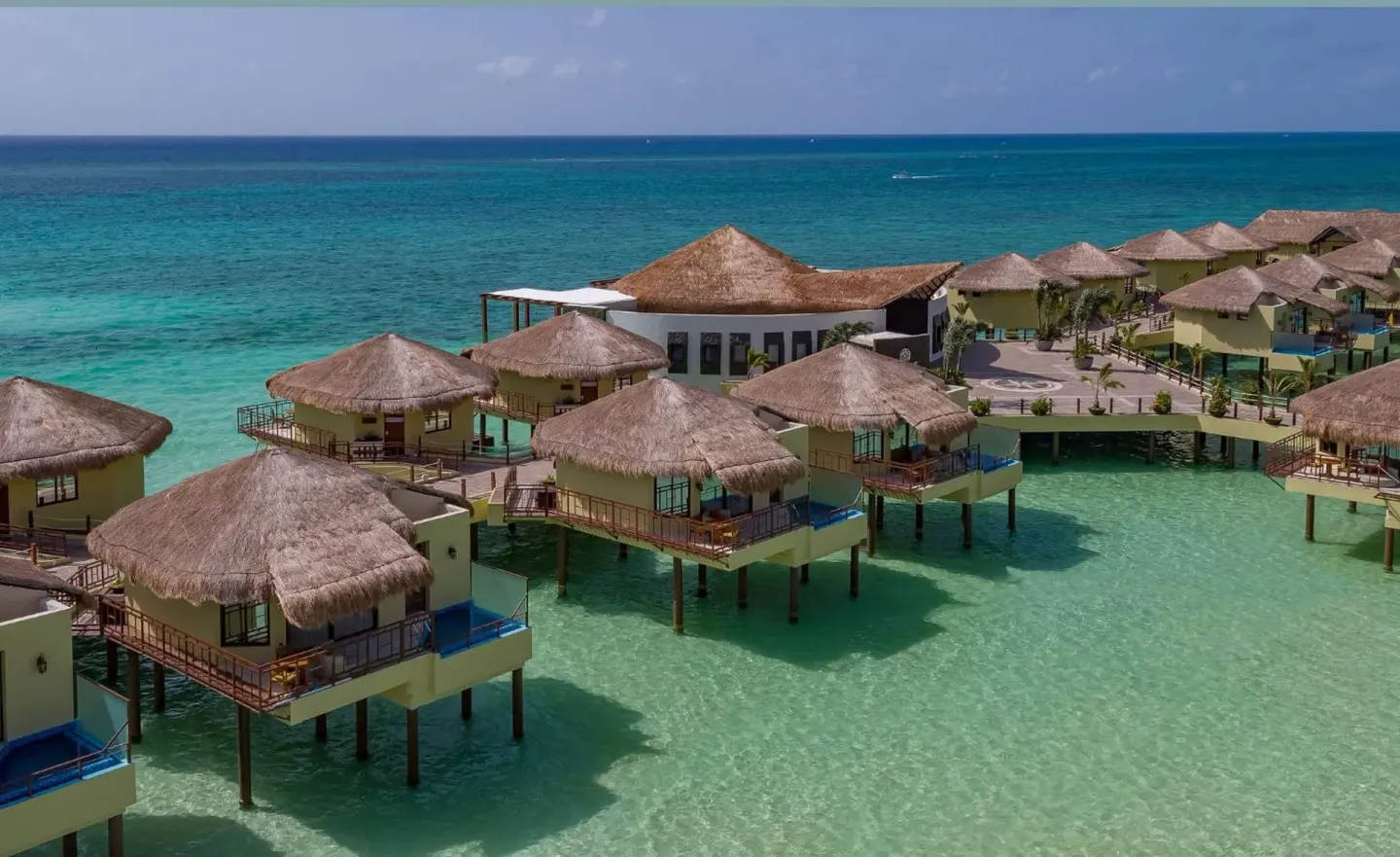 Aerial view of overwater bungalows above turquoise water at Palafitos Overwater Bungalows.