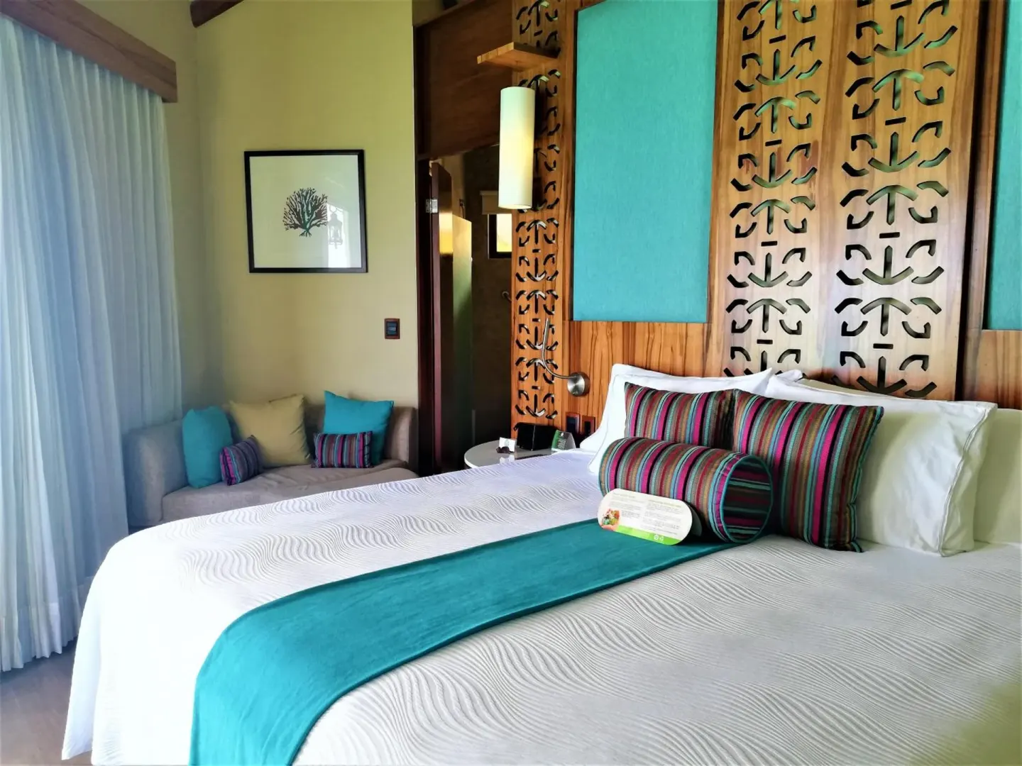 King bed with turquoise accents in a guest bungalow at Palafitos Overwater Bungalows.
