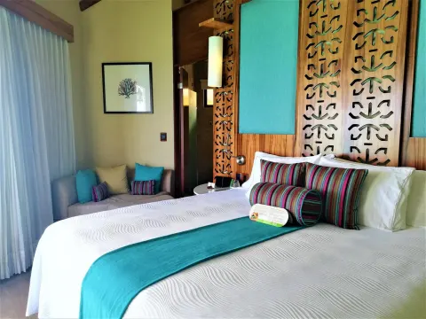 King bed with turquoise accents in a guest bungalow at Palafitos Overwater Bungalows.