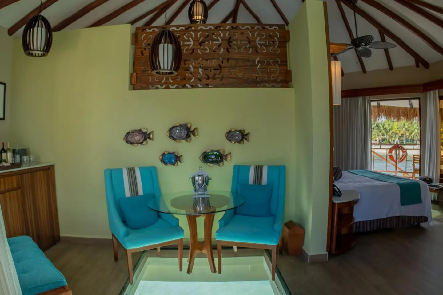 Guest bungalow sitting area and bed at Palafitos Overwater Bungalows.