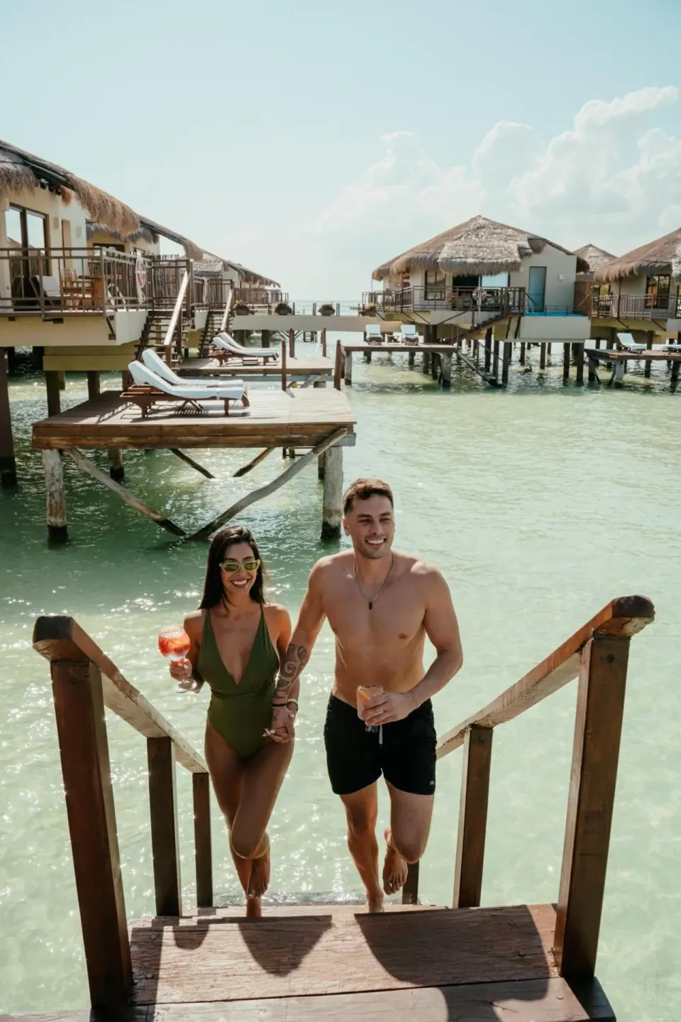 Guests walking from the lagoon among overwater bungalows at Palafitos Overwater Bungalows.