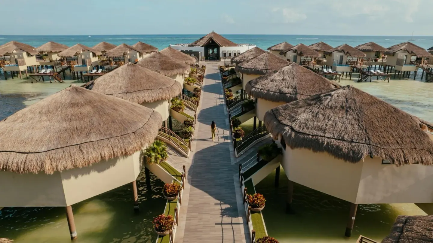 Boardwalk lined with thatched overwater bungalows at Palafitos Overwater Bungalows.