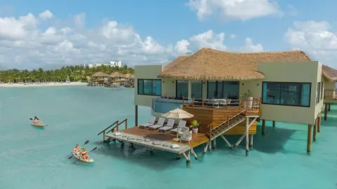 Overwater bungalow deck with lounge chairs and kayakers at Palafitos Overwater Bungalows.