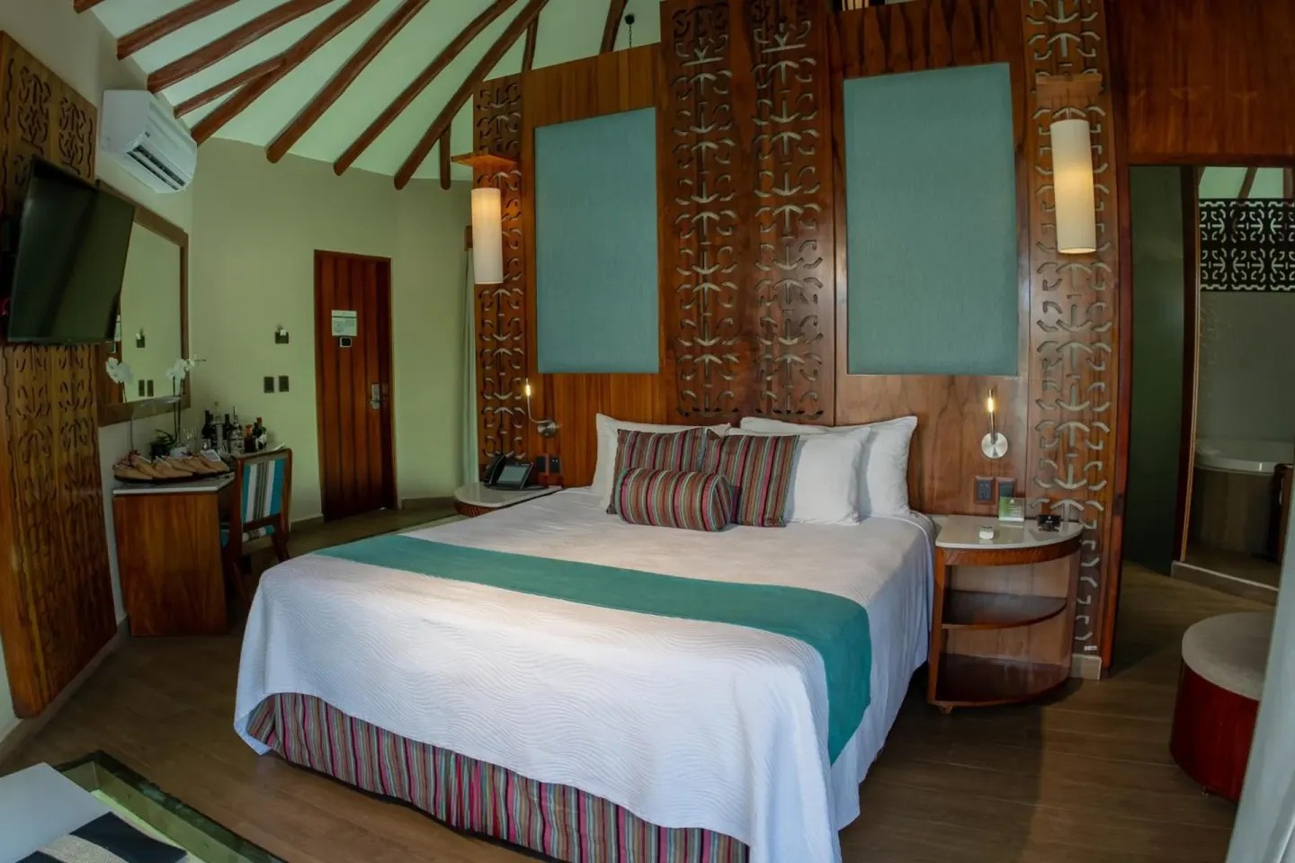 King bed and wood-paneled bedroom interior at Palafitos Overwater Bungalows.