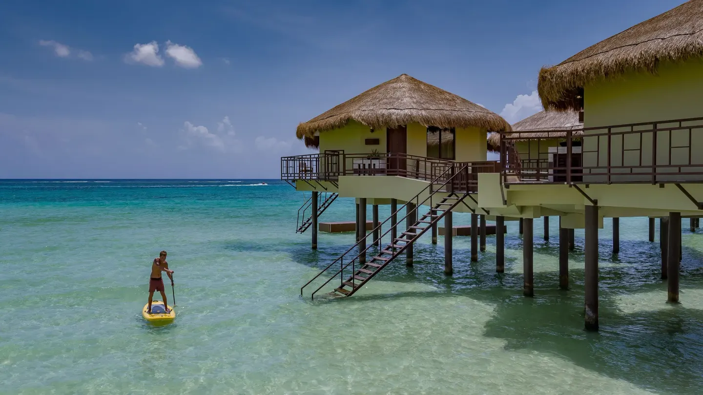 Overwater bungalows and a paddleboarder at Palafitos Overwater Bungalows.
