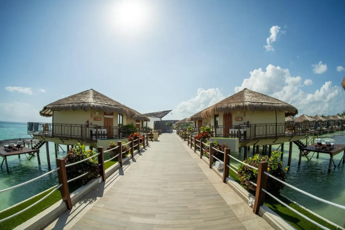 Overwater walkway lined with thatched bungalows at Palafitos Overwater Bungalows.