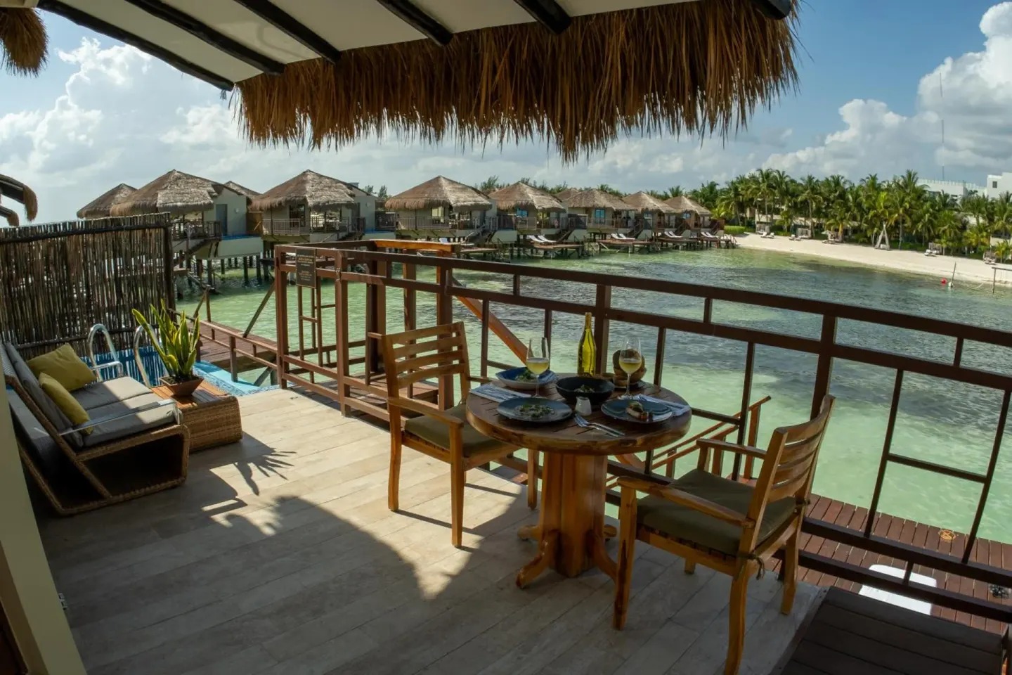 Private bungalow terrace set for dining over the lagoon at Palafitos Overwater Bungalows.
