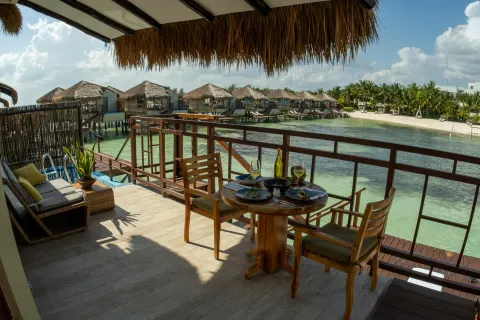 Private bungalow terrace set for dining over the lagoon at Palafitos Overwater Bungalows.