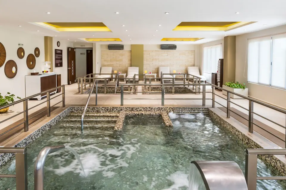 Spa hydrotherapy pool with loungers and railings at Palafitos Overwater Bungalows.