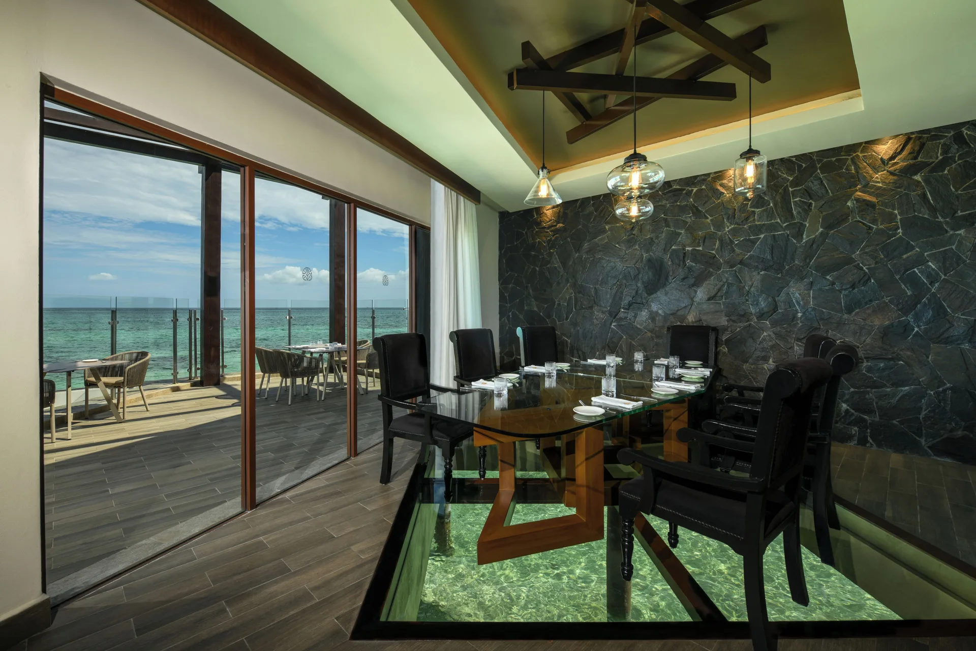 Overwater dining room with glass floor and ocean terrace at Palafitos Overwater Bungalows.