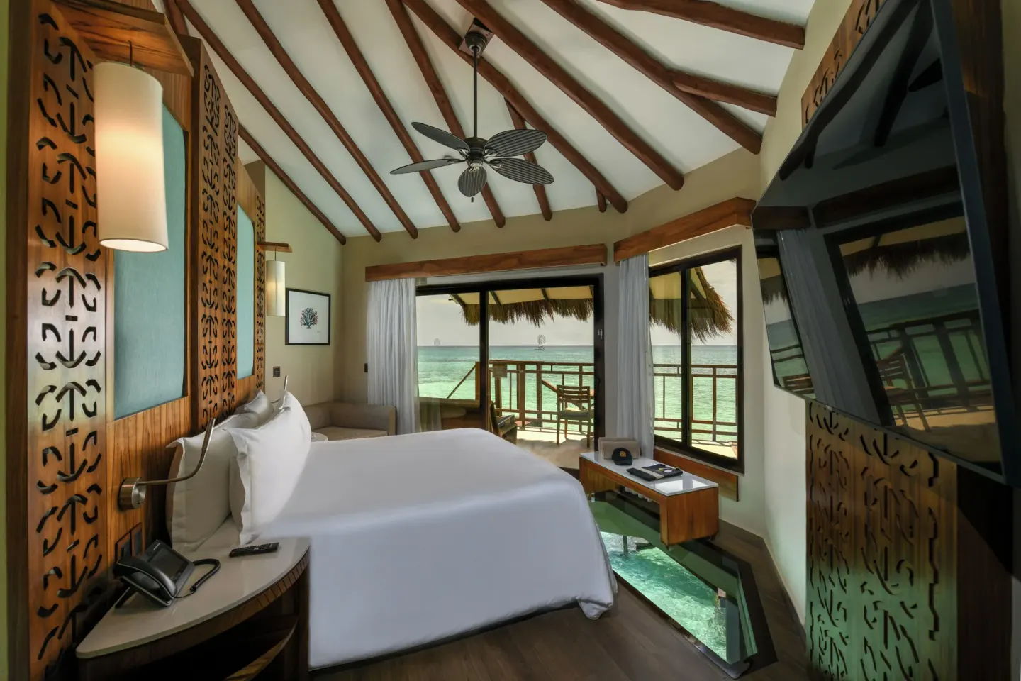 Overwater bungalow king bed and ocean-facing balcony at Palafitos Overwater Bungalows.