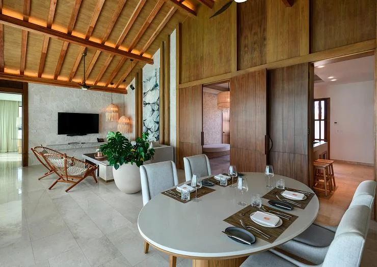 Open dining and living area under a vaulted timber ceiling in the Two Bedroom Presidential Overwater Bungalow.