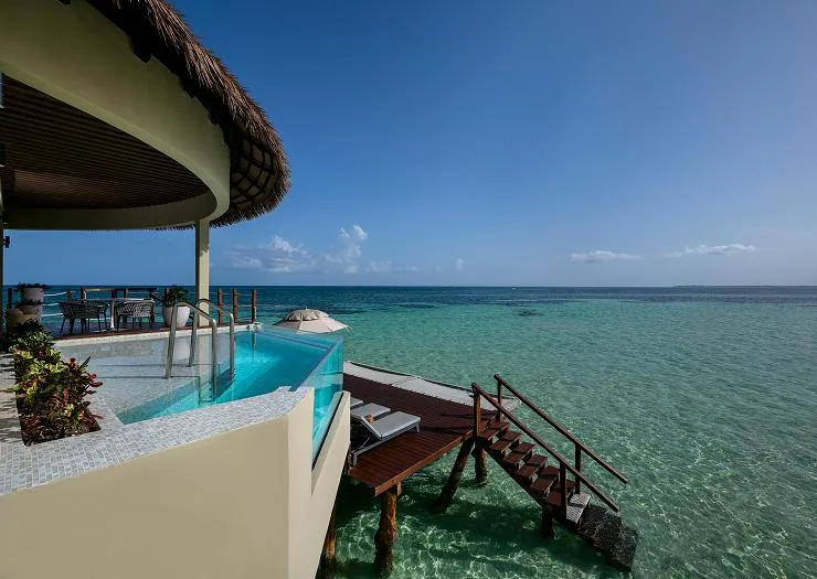 Glass-sided infinity plunge pool and lounger deck over clear lagoon water at the Two Bedroom Presidential Overwater Bungalow.