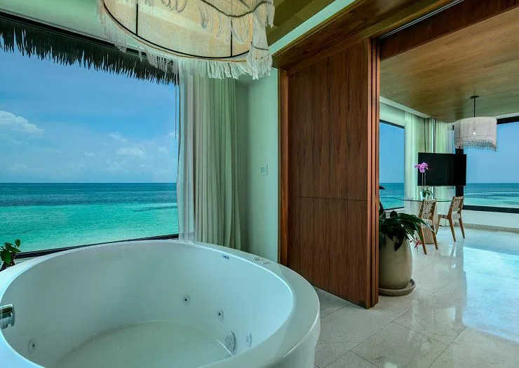 Round in-suite jacuzzi tub set against a floor-to-ceiling ocean window in the Two Bedroom Presidential Overwater Bungalow.