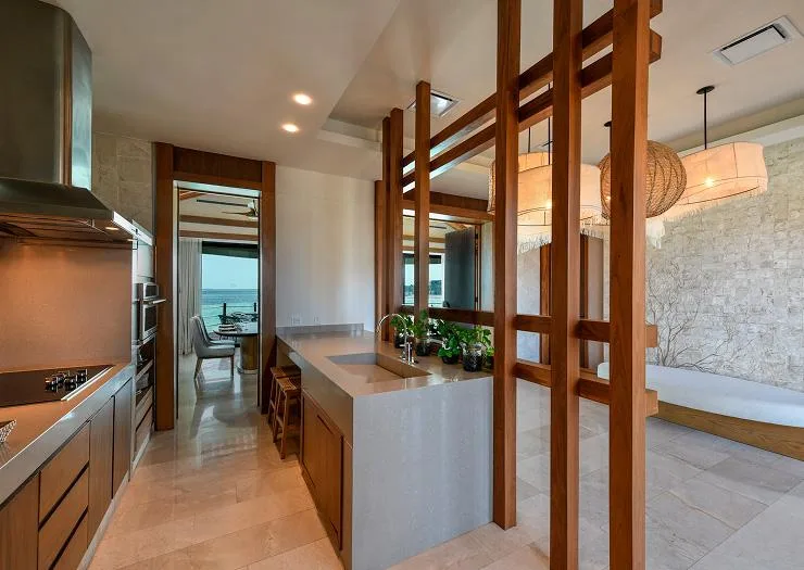 Full kitchen with island and timber screens inside the Two Bedroom Presidential Overwater Bungalow.