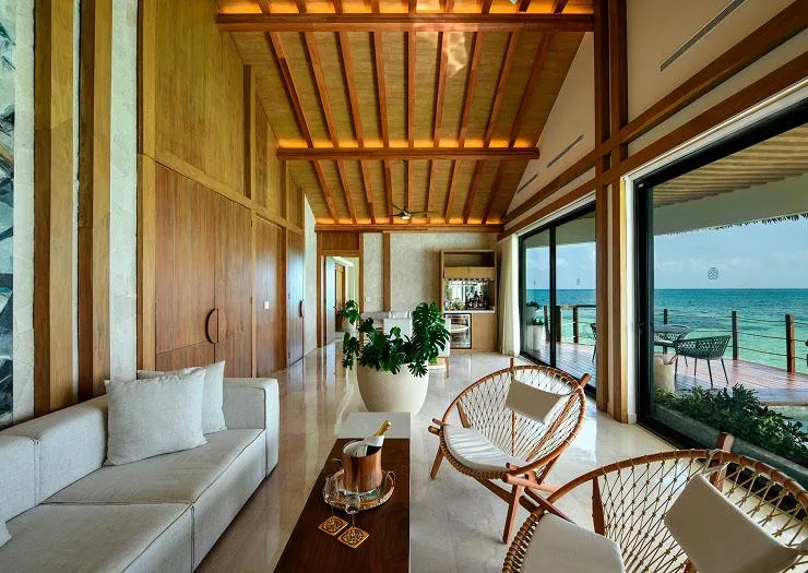 Living room with in-suite bar opening onto the private ocean terrace in the Two Bedroom Presidential Overwater Bungalow.