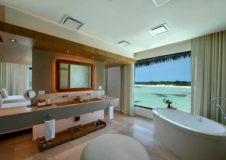 Master bathroom with double vanity and freestanding oval tub facing the lagoon in the Two Bedroom Presidential Overwater Bungalow.