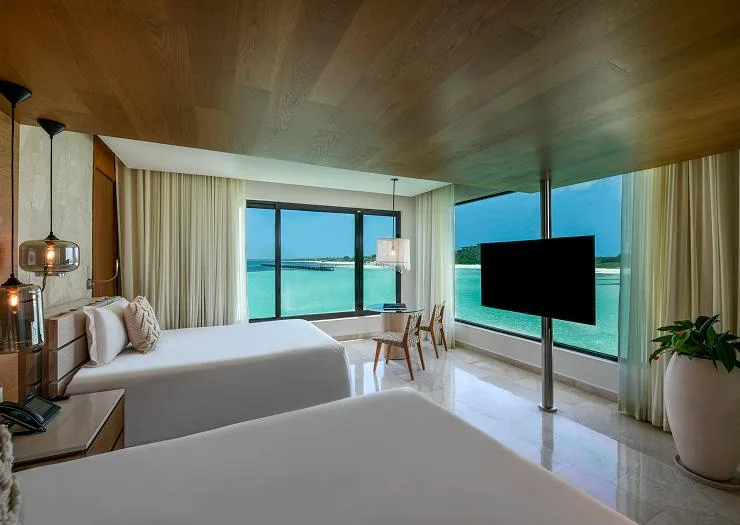 Second bedroom with two double beds and lagoon-view windows in the Two Bedroom Presidential Overwater Bungalow.