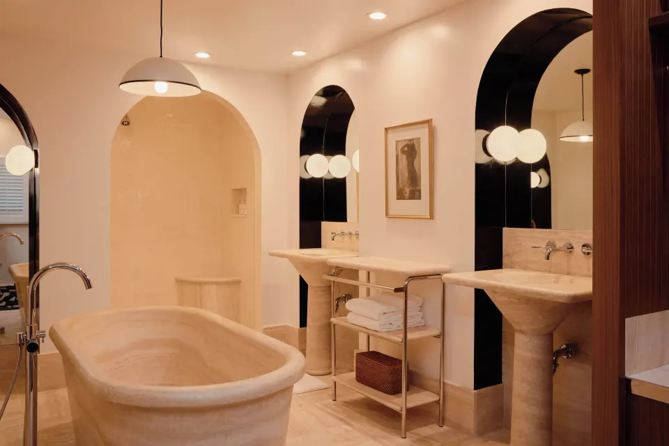 Spacious cream-toned bathroom with free-standing tub and arched mirrors at Palm Heights.