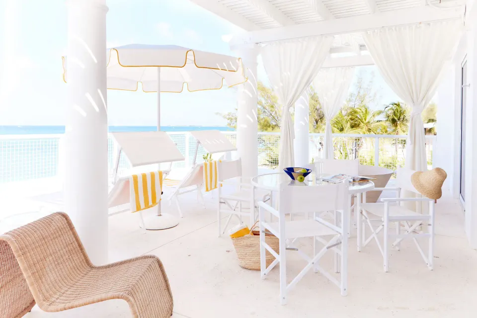 Shaded beachfront terrace with loungers, umbrella and dining table at Palm Heights