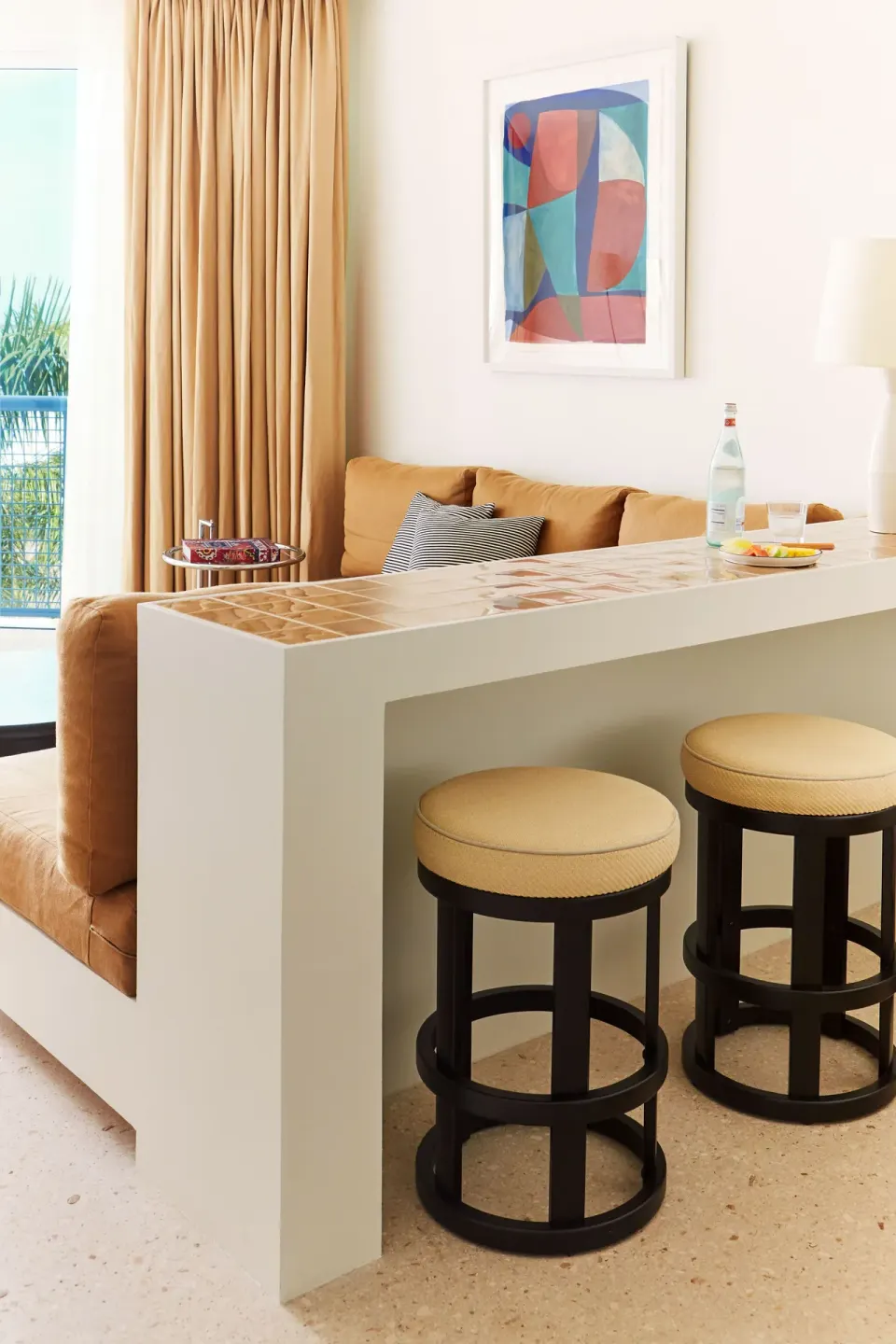 Breakfast bar with two round stools and sofa back in a guest suite at Palm Heights