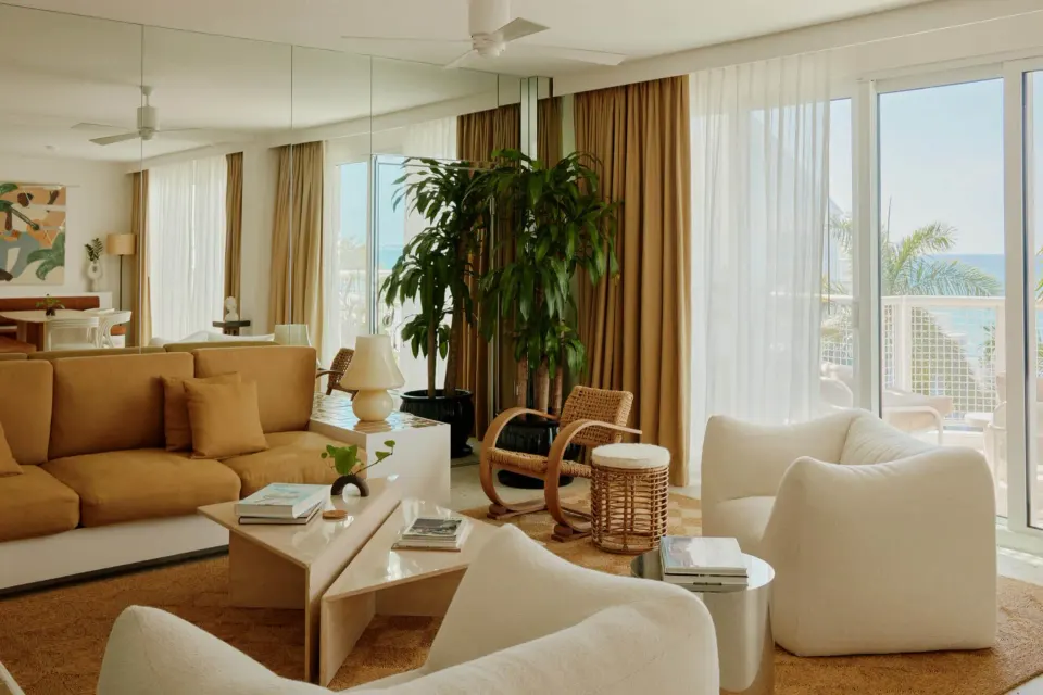 Bright suite living area with large plant and balcony doors at Palm Heights