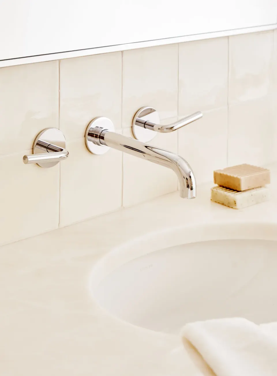 Chrome wall-mounted faucet and round controls above a sink at Palm Heights.