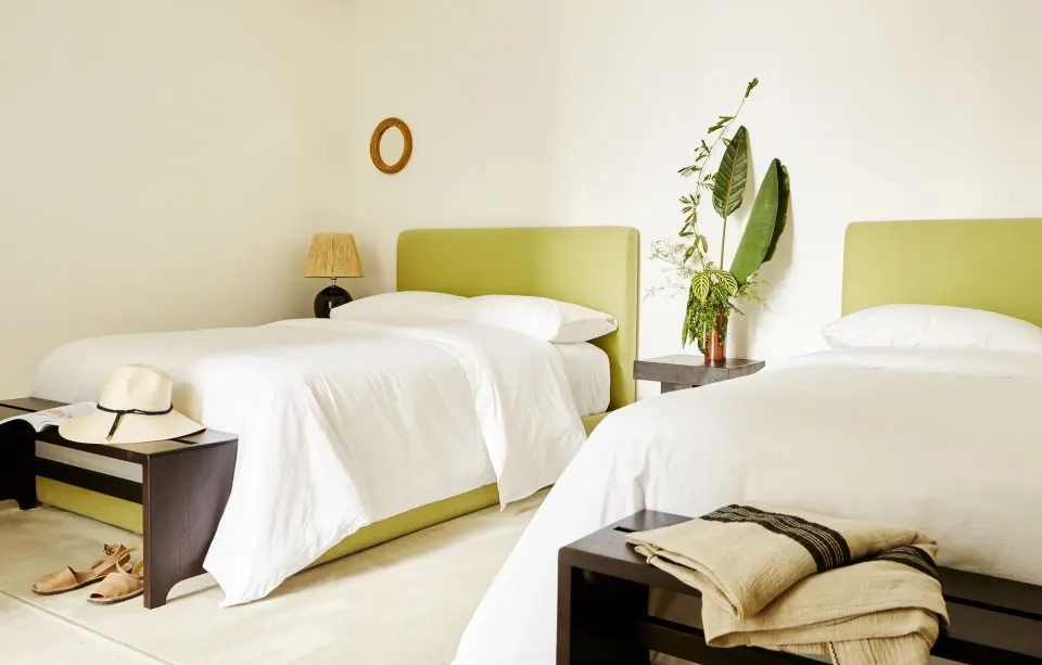 Light bedroom with two twin beds and green headboards at Palm Heights.