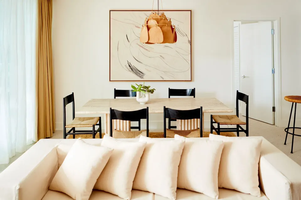 Dining area with six chairs and artwork above, viewed from the sofa at Palm Heights