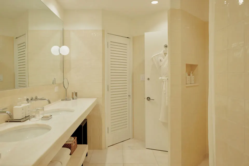 Long vanity with double sinks and a louvered door in a Palm Heights bathroom.
