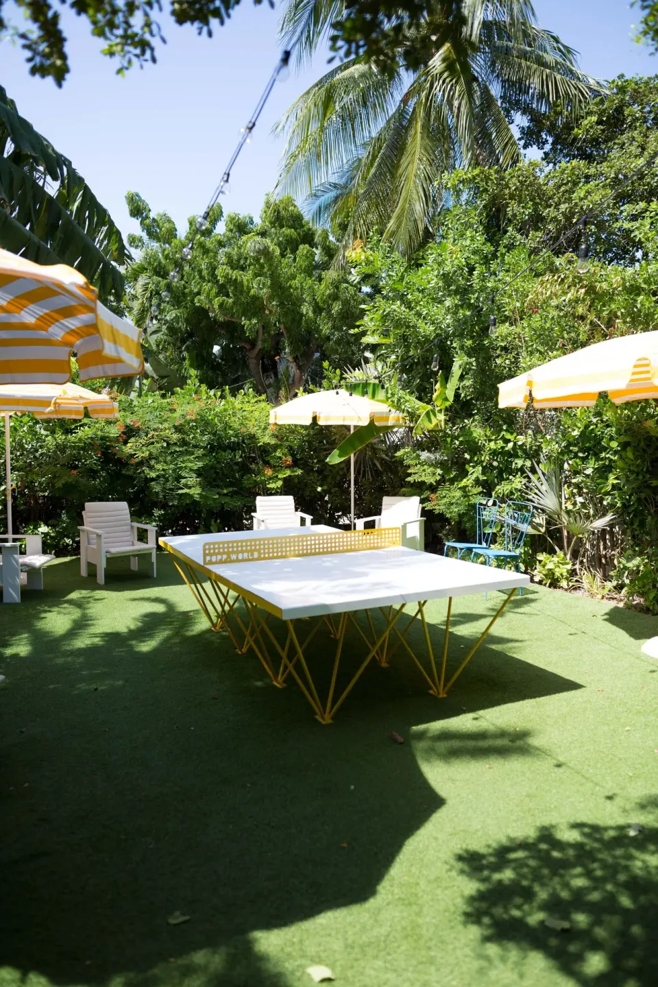 Ping-pong table under umbrellas in a leafy garden at Palm Heights