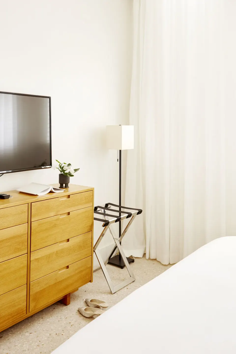 Guest room TV and dresser with luggage rack and lamp at Palm Heights.