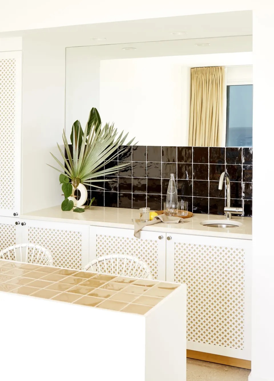 In-room kitchenette with tiled countertop and decorative black tile backsplash at Palm Heights.
