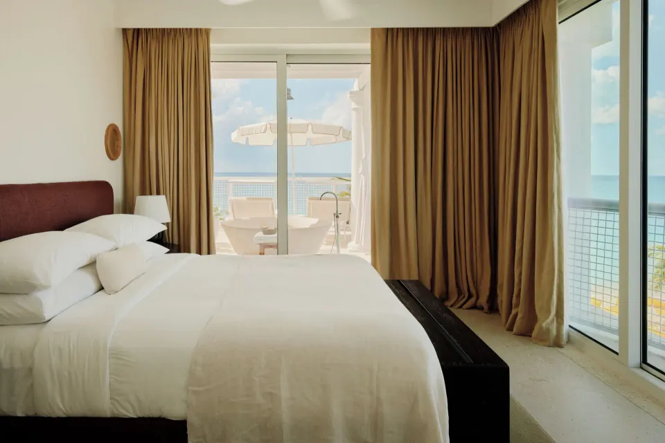 Palm Heights bedroom with a king bed and sliding doors opening to a balcony overlooking the sea.