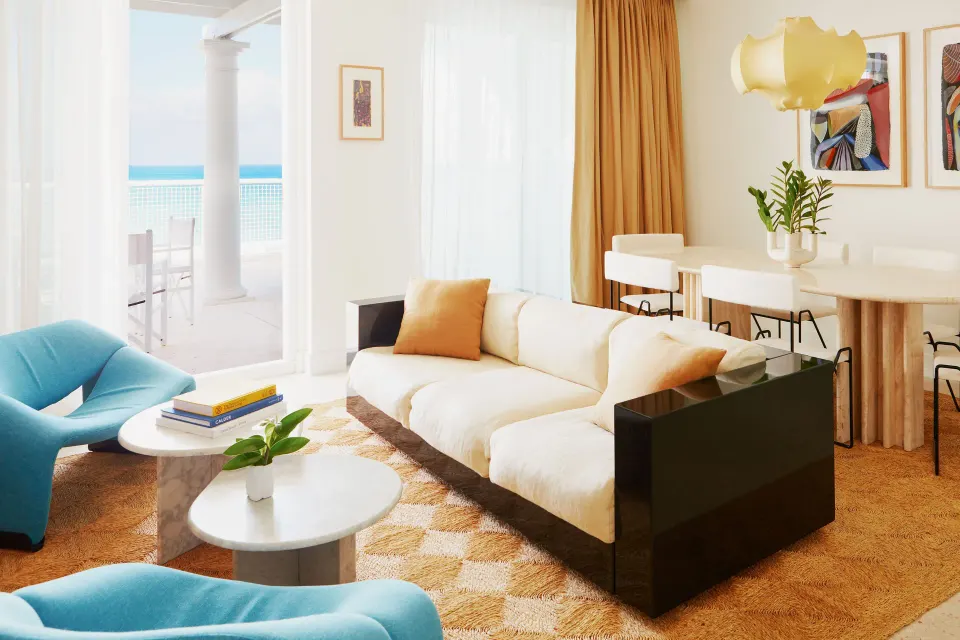 Bright suite living area with blue armchairs and balcony view at Palm Heights